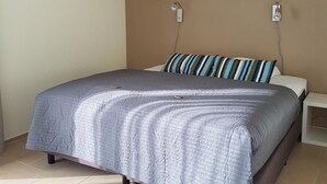 Una camera da letto con un letto, un comodino, un quadro appeso al muro e una presa elettrica.