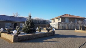 Un cortile con un edificio in mattoni, un abete innevato e decorazioni sferiche.
