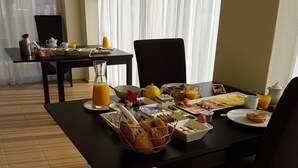 Una colazione preparata con tavolo, sedie e una finestra con tende.