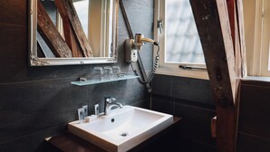 A bathroom with a white sink, a mirror, and a hairdryer on a shelf. - Hotel Corner House (Amsterdam)