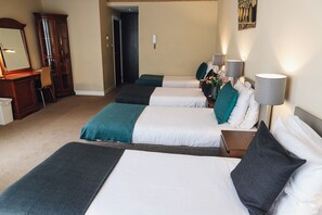 A hotel room with three beds, a wooden cabinet, a mirror, and a wall-mounted lamp. - Hotel Corner House (Amsterdam)