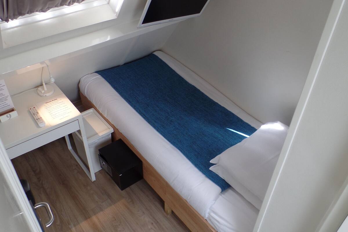 A compact room with a bed, a desk, and a window.
