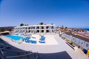 Alberca al aire libre, sombrillas en la alberca y camastros