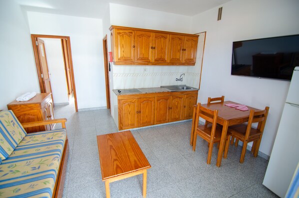A compact kitchen with wooden cabinets, a built-in sink, and a dining area with a table and chairs.