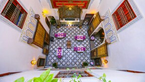 A traditional Moroccan interior with a central seating area, ornate wall decorations, and patterned flooring. - Dar Attajalli (Fes)