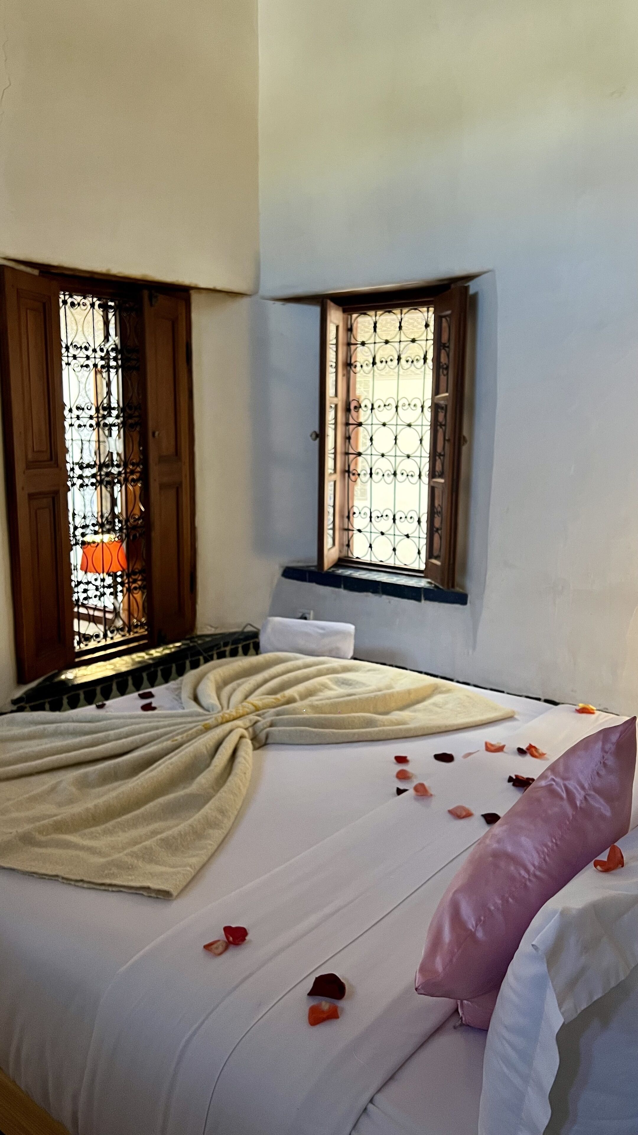 A bedroom with a bed, a window with a metal grill, and a wooden door.