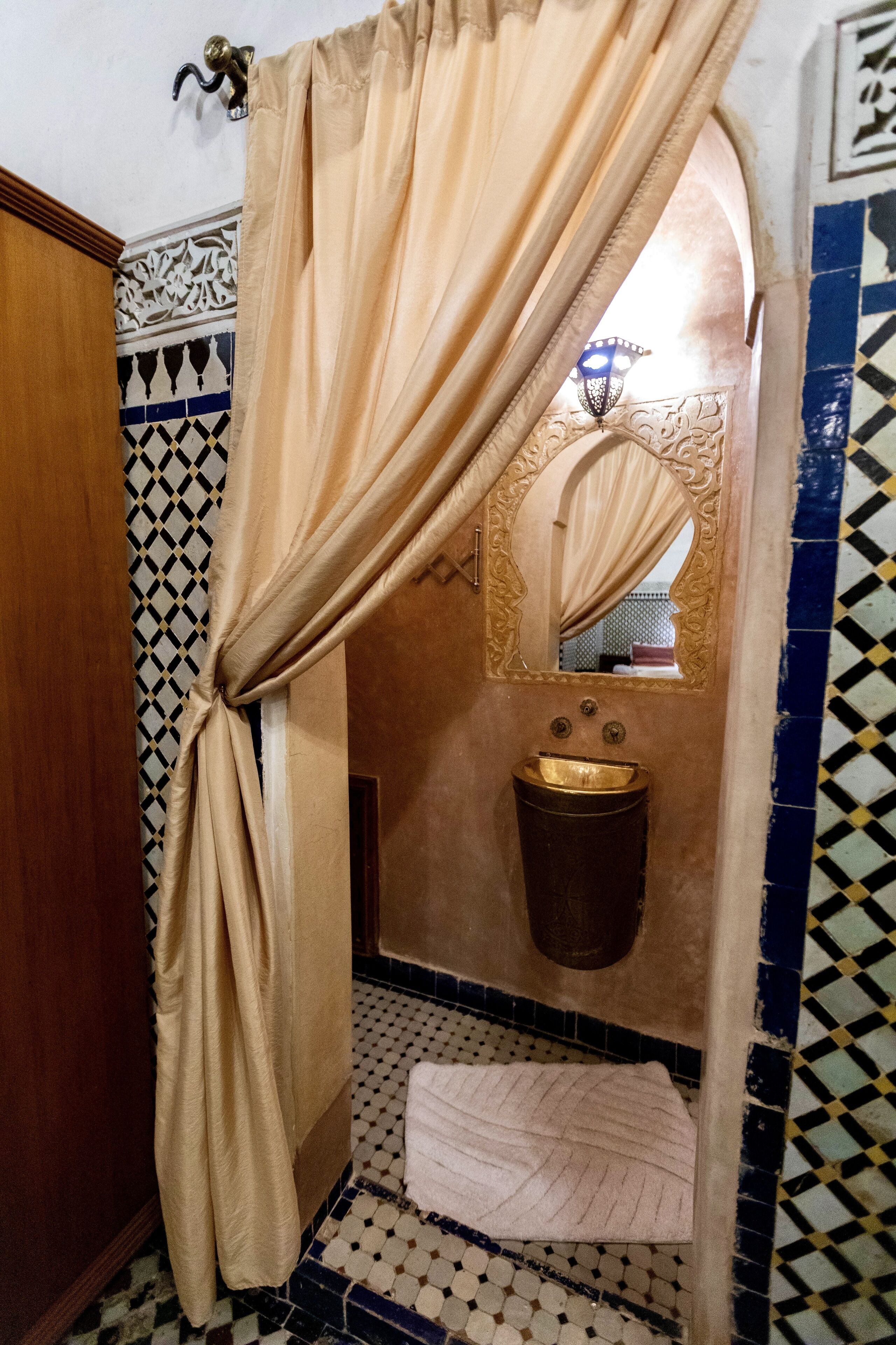 Un baño con piso estampado, un lavamanos y un espejo.