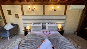 A bedroom with a large bed, two bedside lamps, a chandelier, and a wooden ceiling. - Dar Attajalli (Fes)