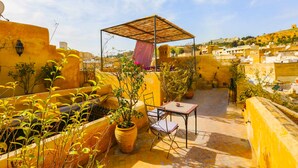 A rooftop terrace with a pergola, potted plants, a table, and chairs. - Dar Attajalli (Fes)