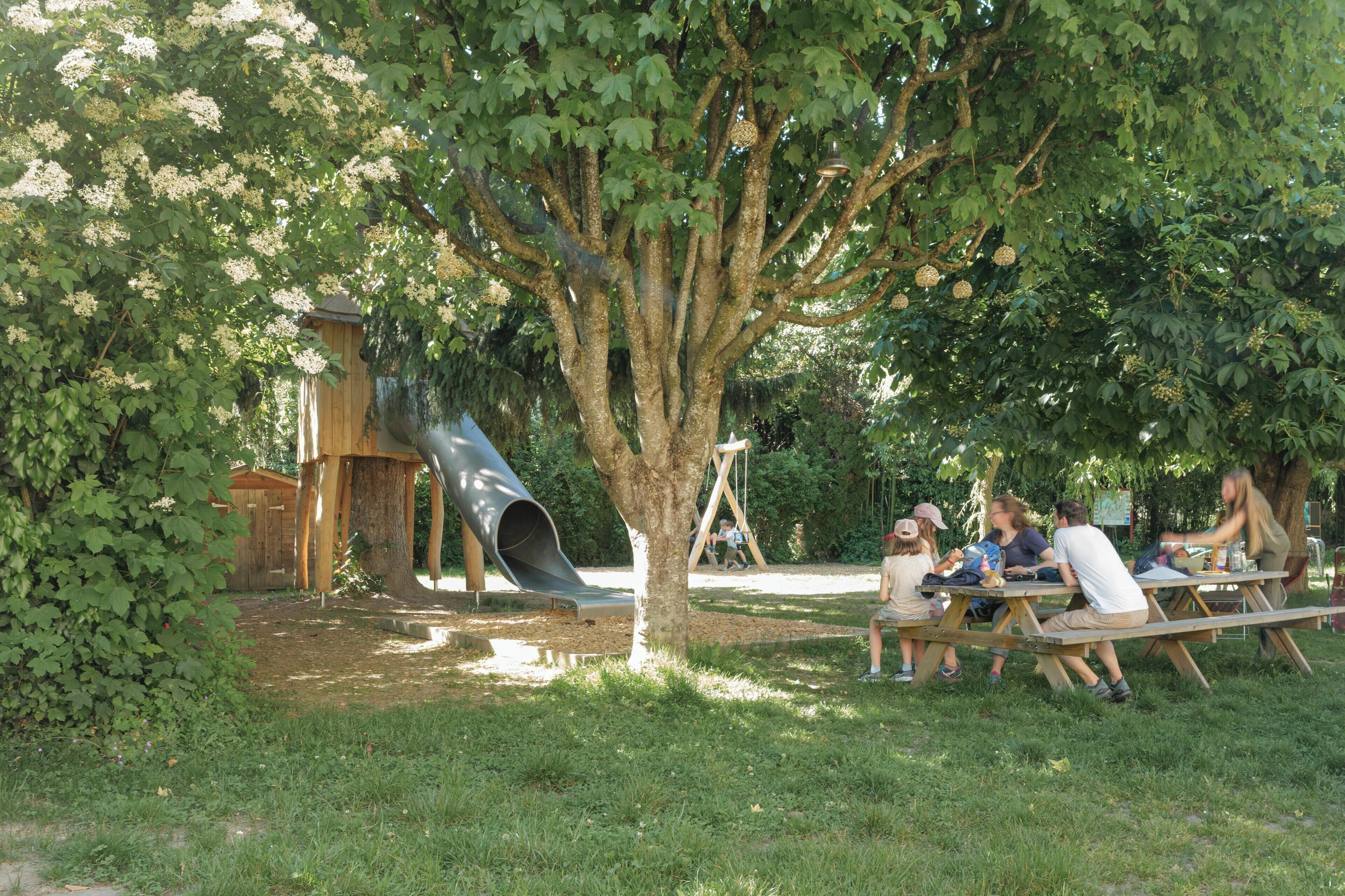 Ein Picknickplatz mit Tischen, Bänken, einer Rutsche und einer Schaukel.