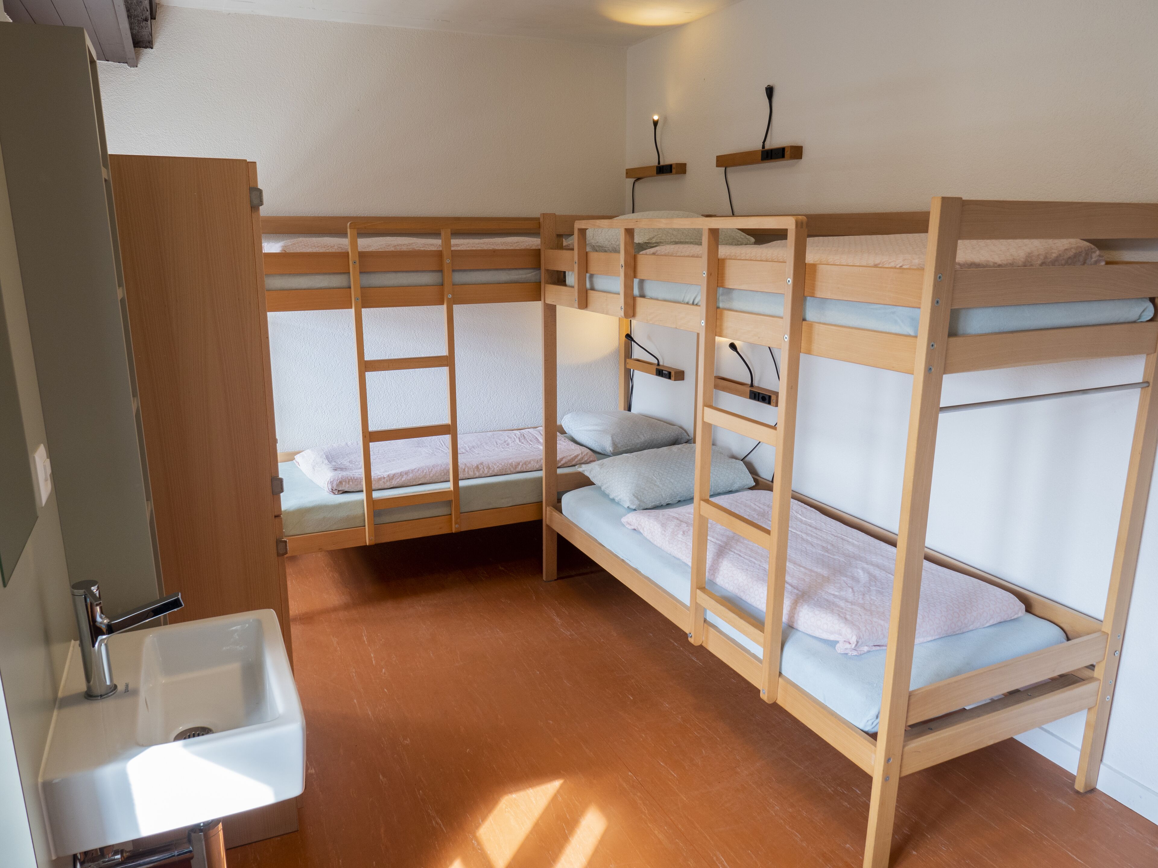 Une chambre avec un lit superposé, un lavabo et une échelle.