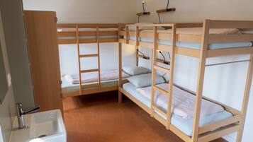 Une chambre avec un lit superposé, un lavabo et une échelle.