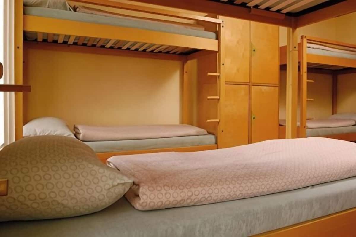 A bunk bed room with wooden walls and a bunk bed. There are pillows on the beds.