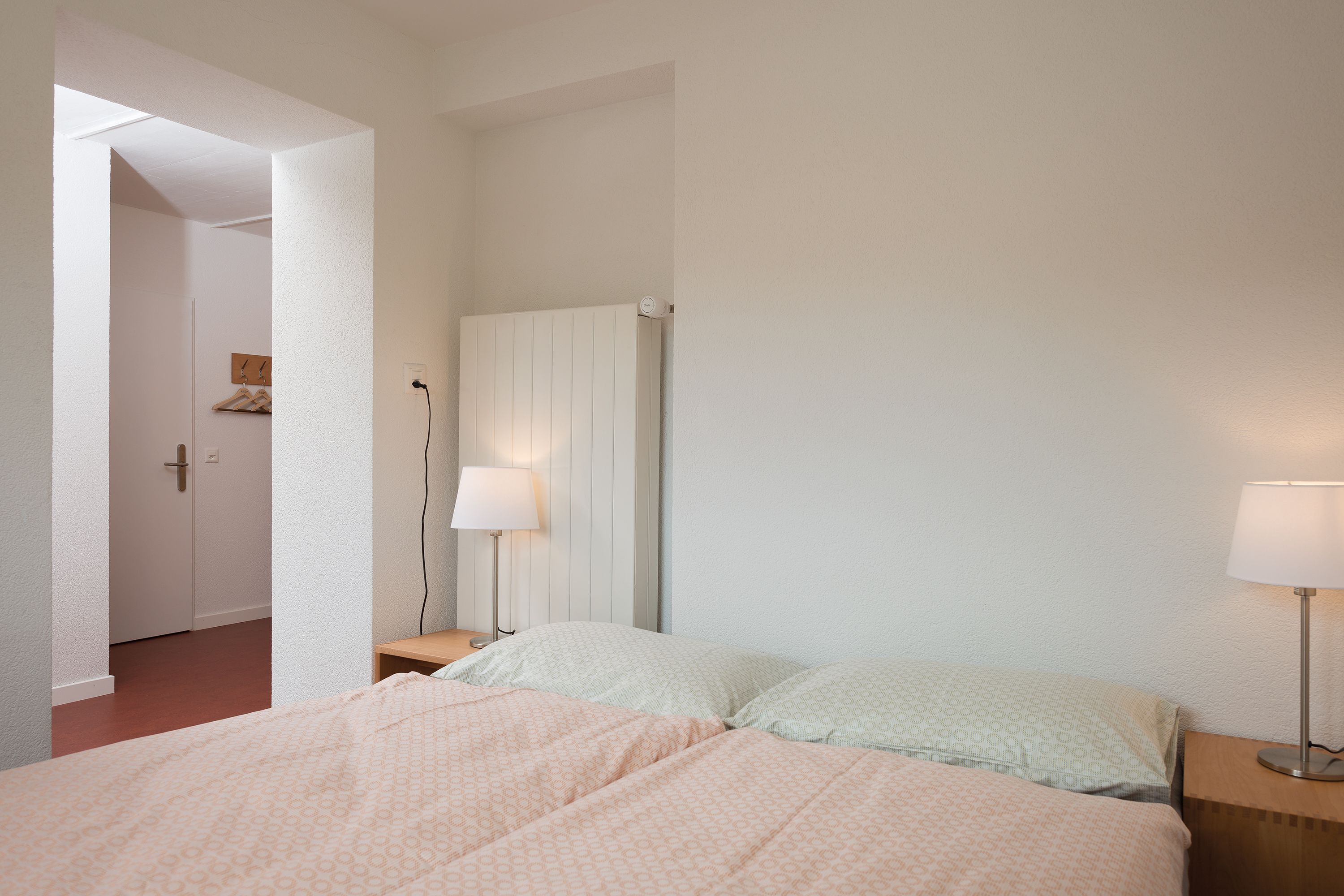 Une chambre à coucher comprenant un lit, deux tables de chevet avec des lampes, une armoire et un miroir.