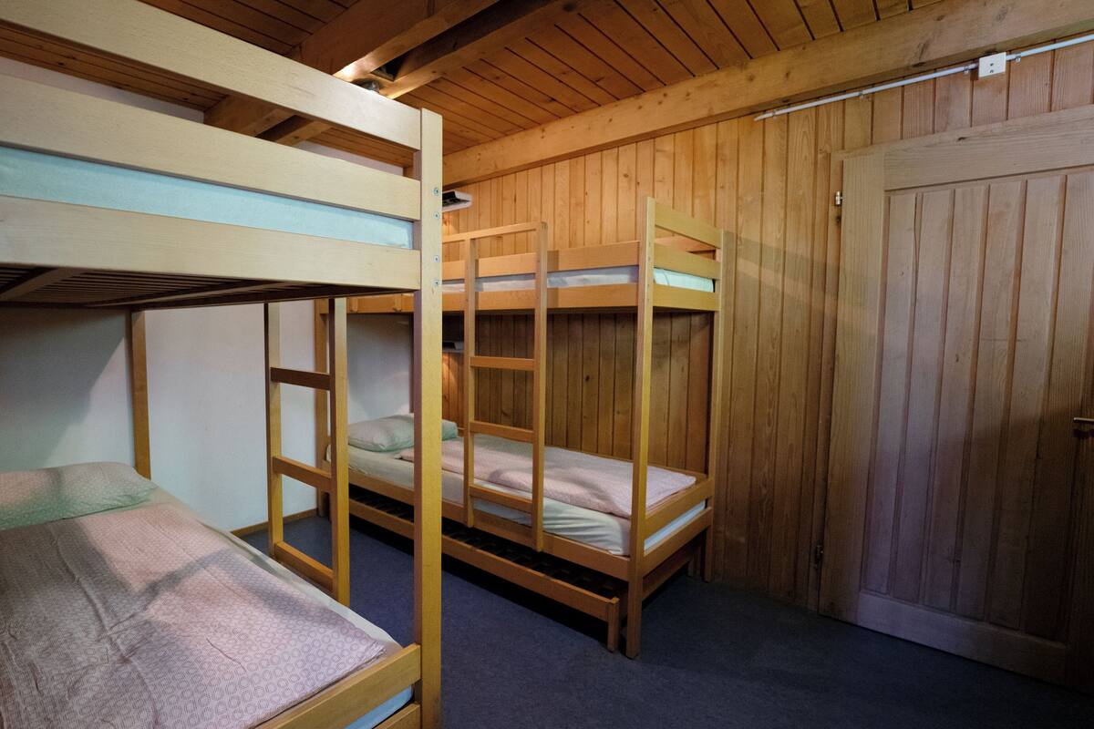 A room with bunk beds, wooden walls, and a door.