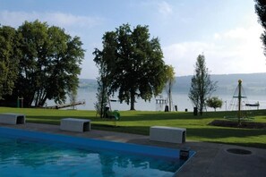Una piscina con vistas a un lago y árboles.