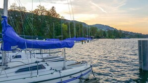 A marina with several sailboats docked, a wooden pier, and a backdrop of hills and trees. - Youth Hostel Beinwil am See (Beinwil am See)