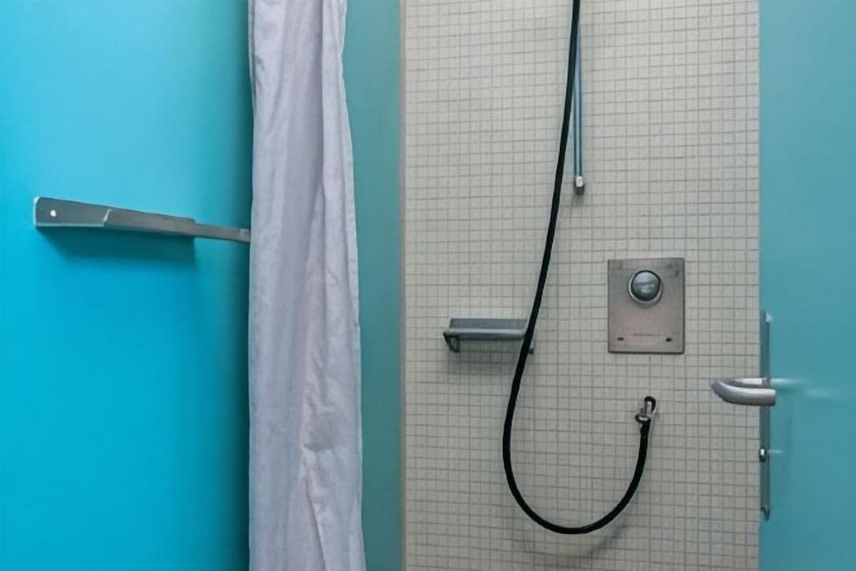 A bathroom with a shower, a towel rack, and a door with a handle.