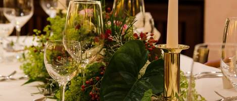 A table set for dining with white tablecloths, clear glassware, and a lit candle.