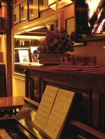 Un piano con partituras, un espejo y un florero.