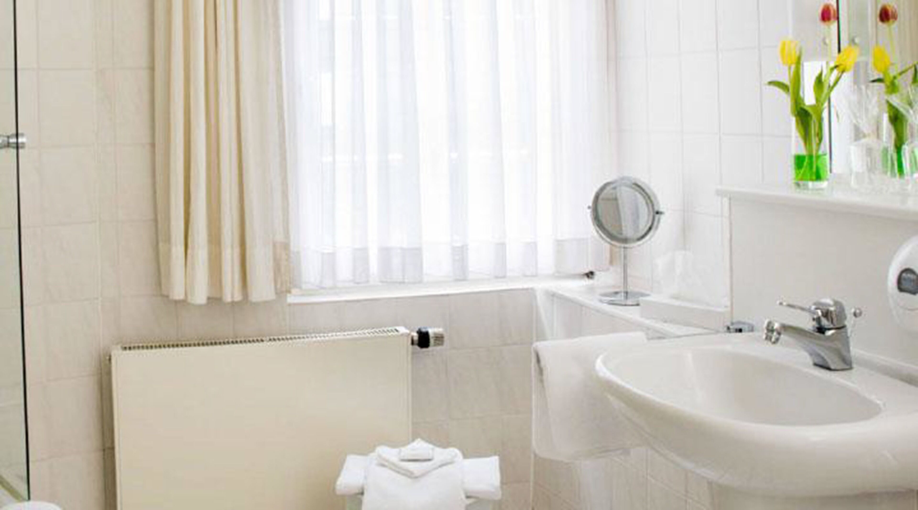 A bathroom with a white sink, mirror, and radiator.