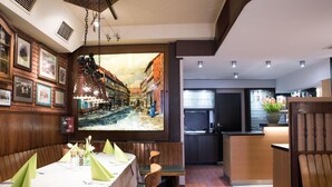 Een restaurant met een lange eettafel, zitjes en een keukenhoek.
