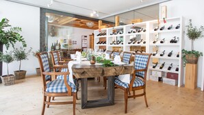 A restaurant with a wooden table and chairs, surrounded by shelves of wine bottles. - Posthotel Valbella - Berge, Spa & Wir (Vaz-Obervaz)