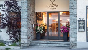 A stone facade with a sign for "Posthotel Valbella" and large potted plants at the entrance. - Posthotel Valbella - Berge, Spa & Wir (Vaz-Obervaz)
