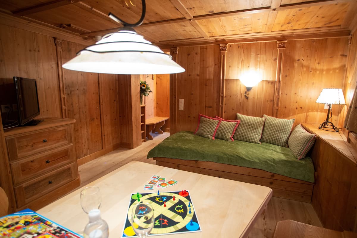Une pièce chaleureuse en bois, avec un lit, une table sur laquelle est posé un jeu de société, un téléviseur et une lampe.