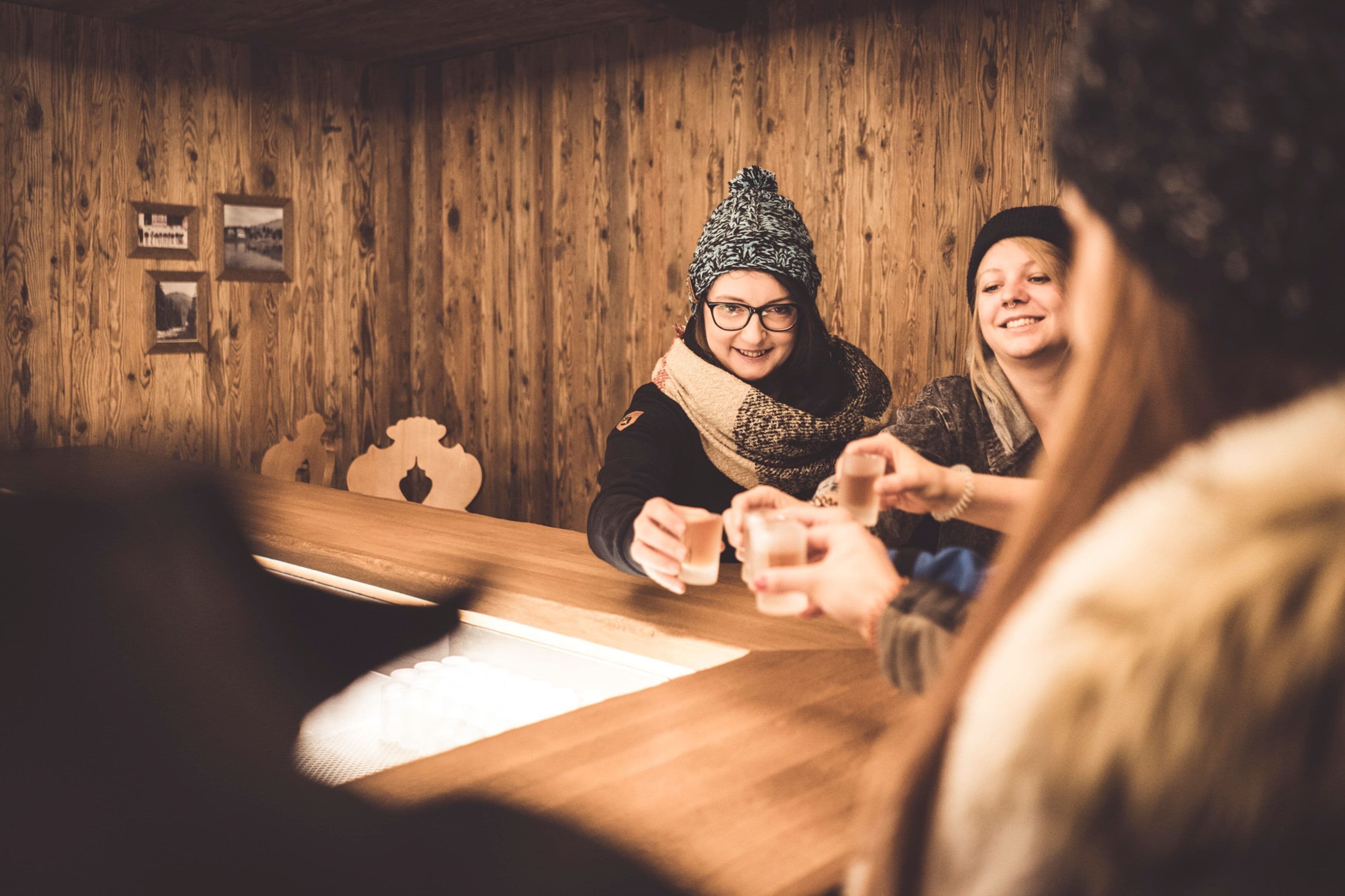 A wooden interior with a table where people are seated, engaged in conversation.