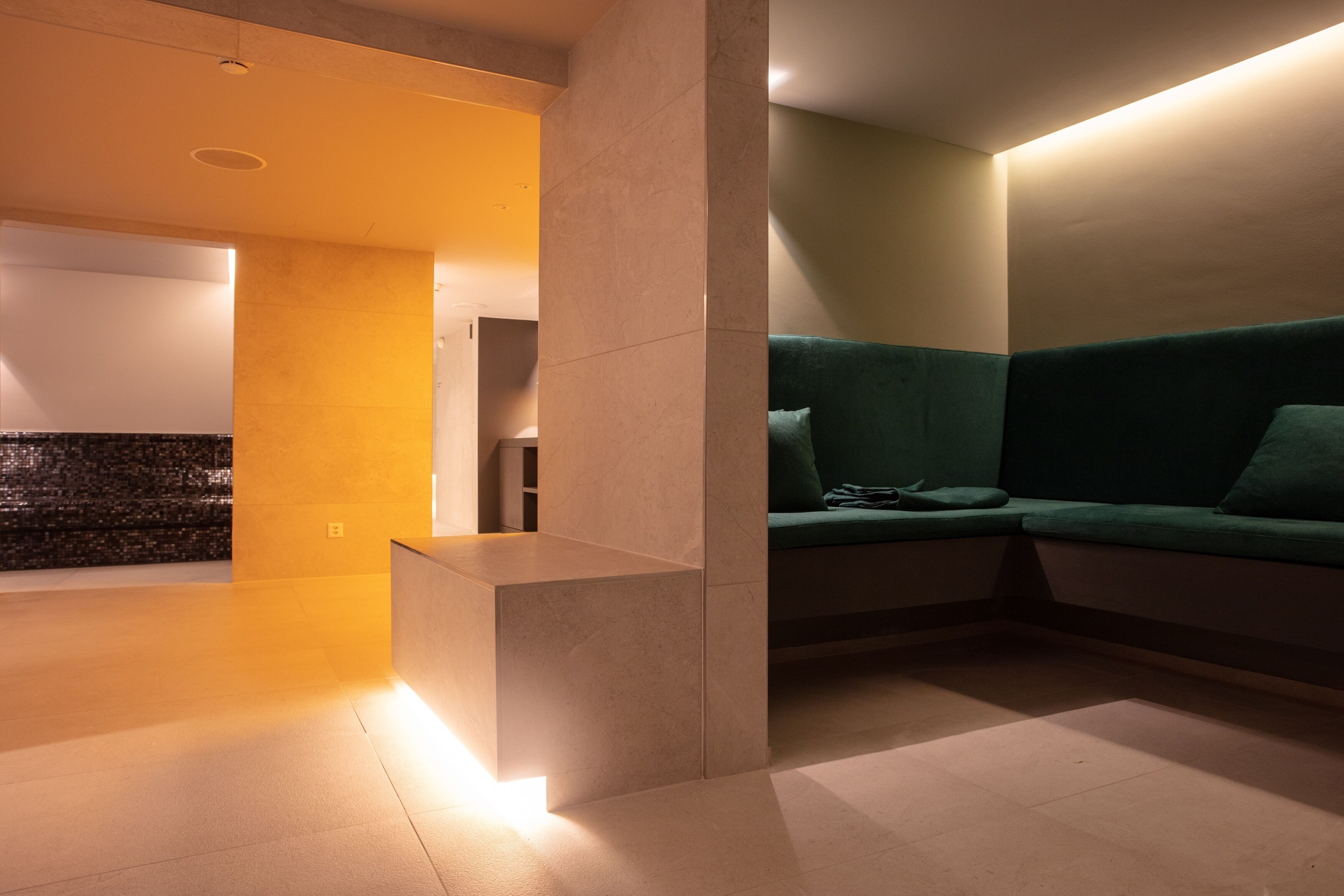 A modern interior with a green sofa, a small table, and a tiled floor.