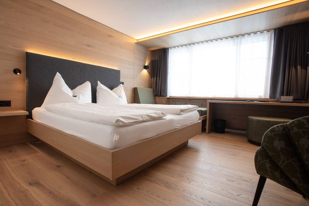 Une chambre d’hôtel moderne, dotée d’un grand lit, d’un bureau et d’une chaise.