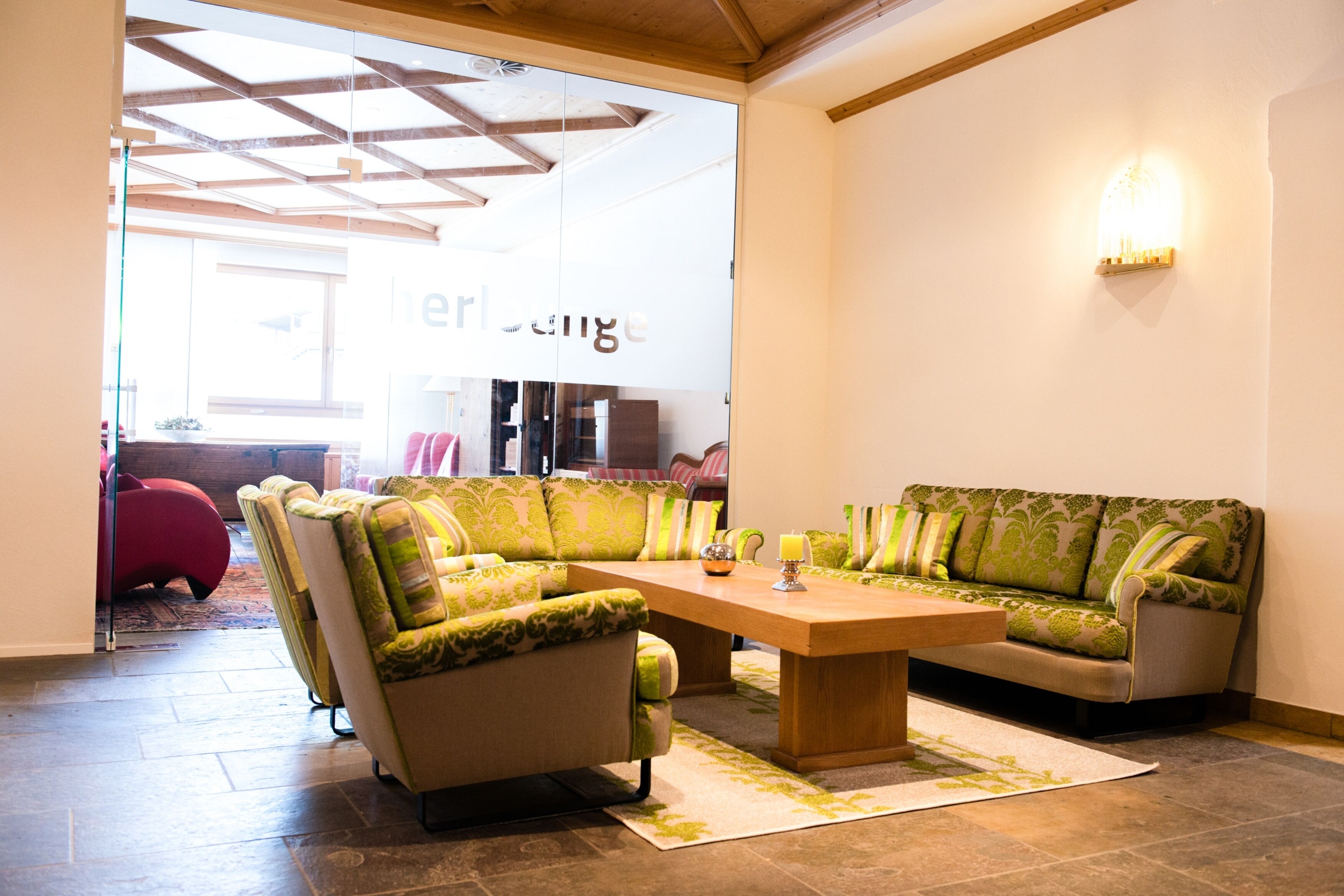 A modern living room with a wooden ceiling, a large sofa set, and a coffee table.