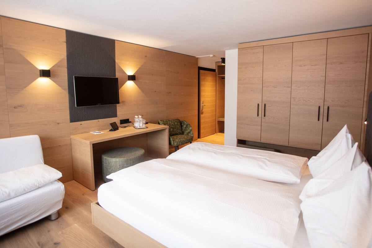 Une chambre d’hôtel moderne dotée d’un grand lit, d’un bureau avec une chaise, d’un téléviseur à écran plat fixé au mur et d’une armoire.