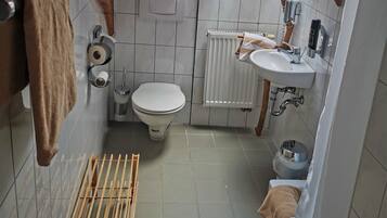 A compact bathroom with a toilet, sink, and shower area.