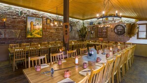 A rustic dining area with wooden tables and chairs, stone walls, and a chandelier. - Hotel Drei Lilien (Werbach)