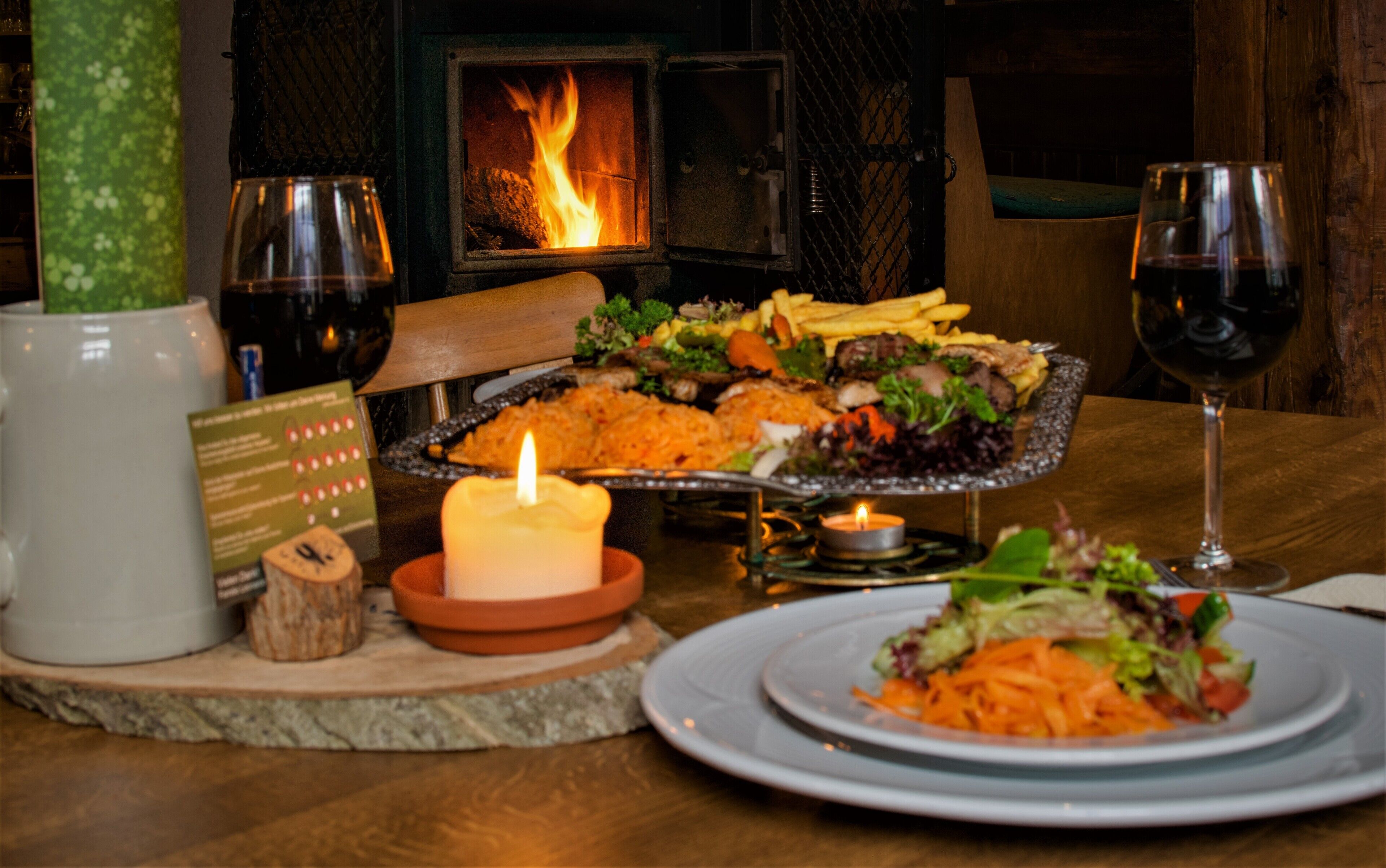 A dining table with a variety of dishes, candles, and glasses of wine.
