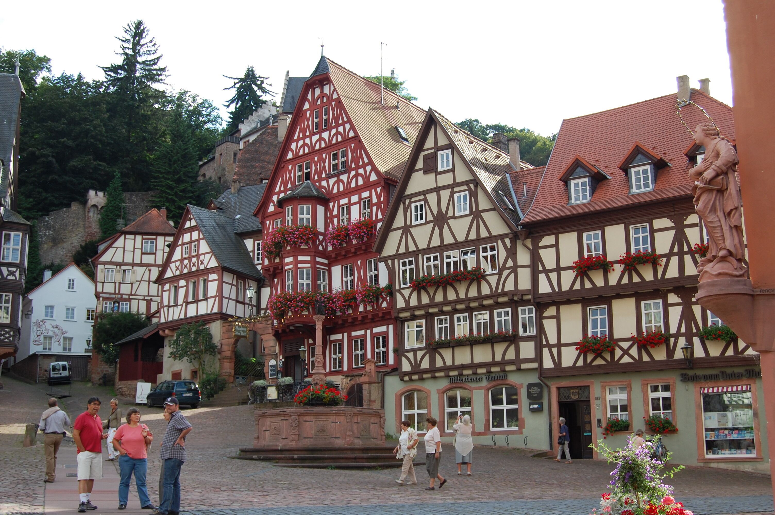 A traditional half-timbered building with a central courtyard, a fountain, and flower boxes on the windows.