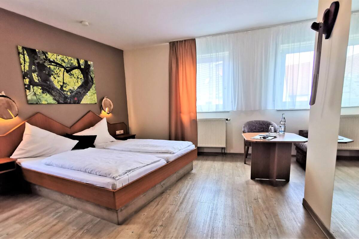 A hotel room with a bed, bedside tables, a desk, and a chair.