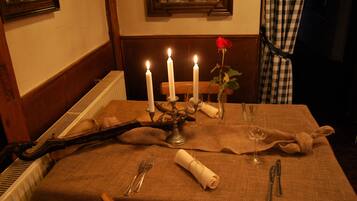 Una mesa de comedor dispuesta con velas, una rosa y cubiertos.