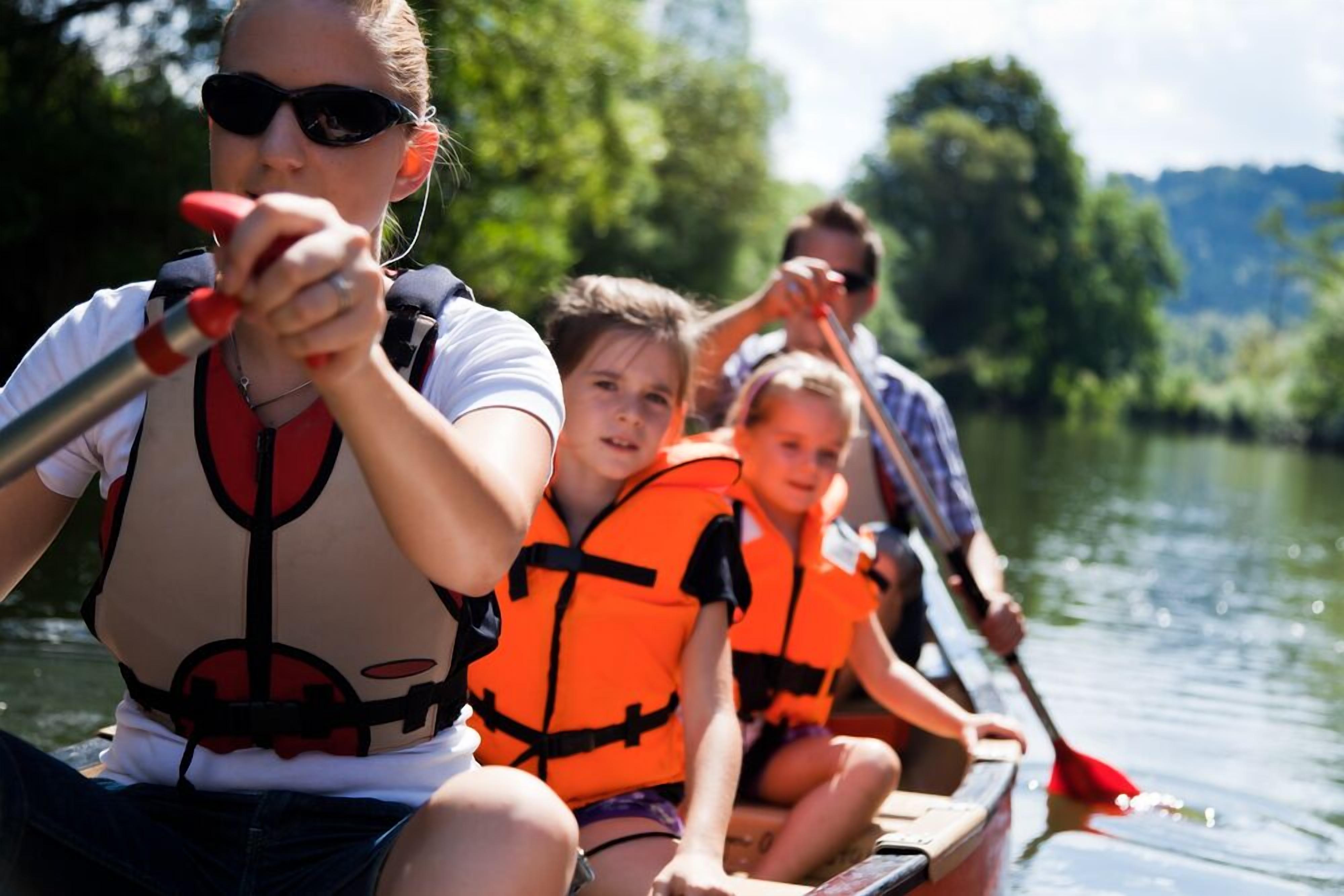 A group of people in a boat on a river, wearing life jackets.