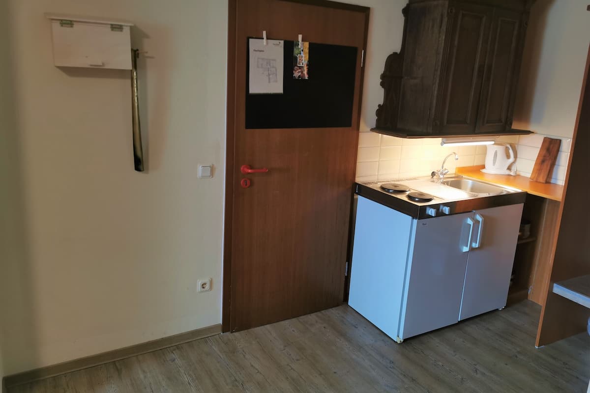 A compact kitchen with a wooden cabinet, a white refrigerator, and a small countertop.