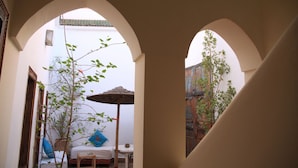 An arched corridor with a bed, a small table, and a chair. - Riad le Coq Fou (Marrakech)