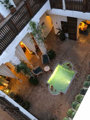 A courtyard with a pool, seating area, and potted plants. - Riad le Coq Fou (Marrakech)