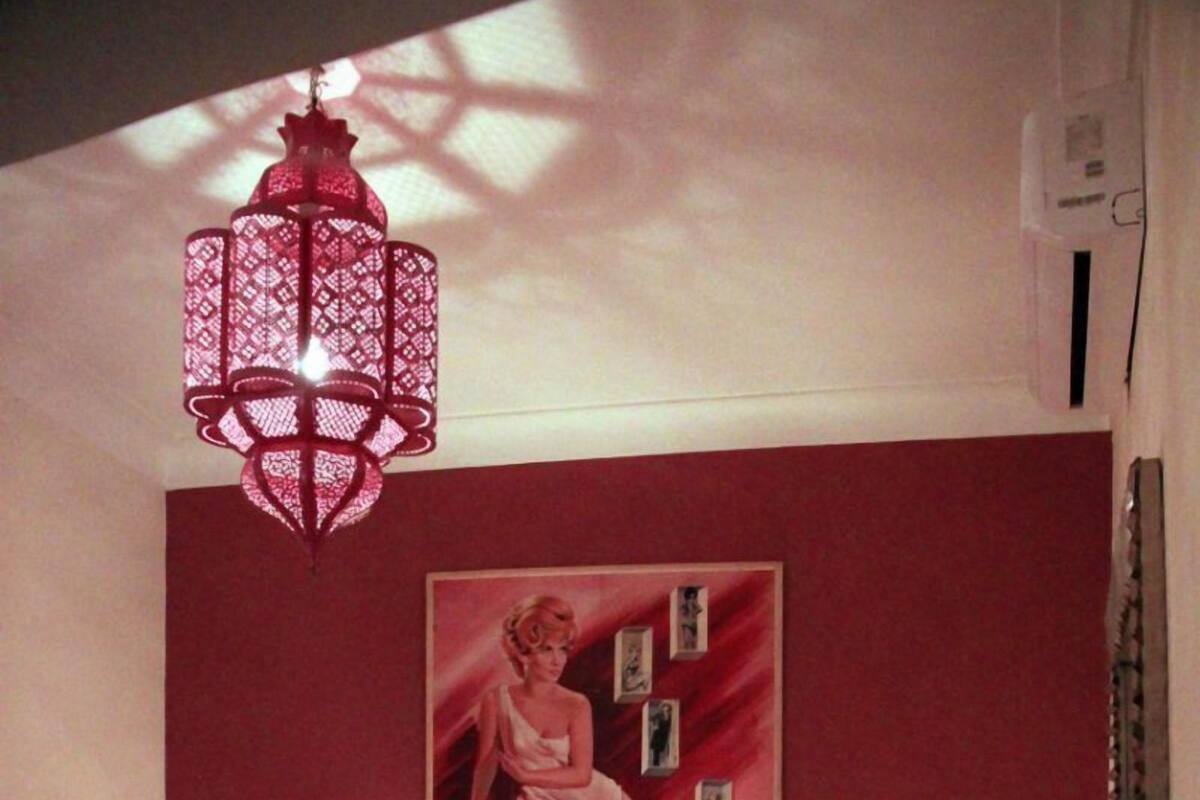 A bedroom with two beds, a poster on the wall, a hanging light fixture, and a checkered floor.