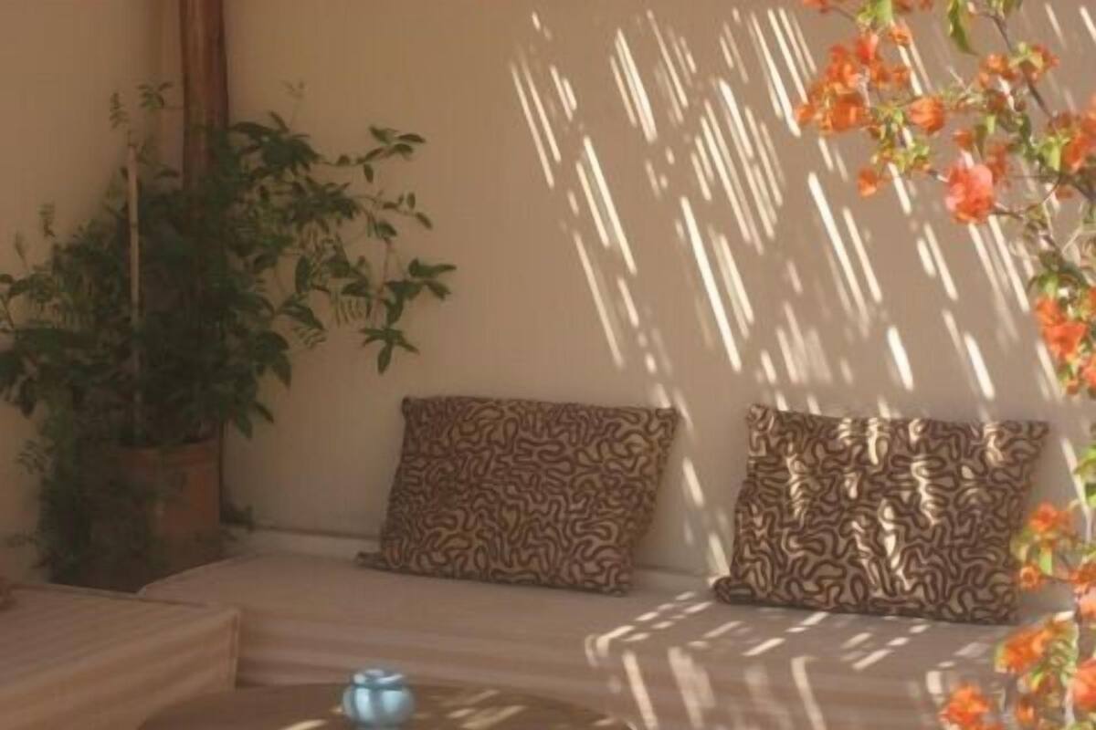 A cozy seating area with patterned cushions, a round table with a candle, and a potted plant.
