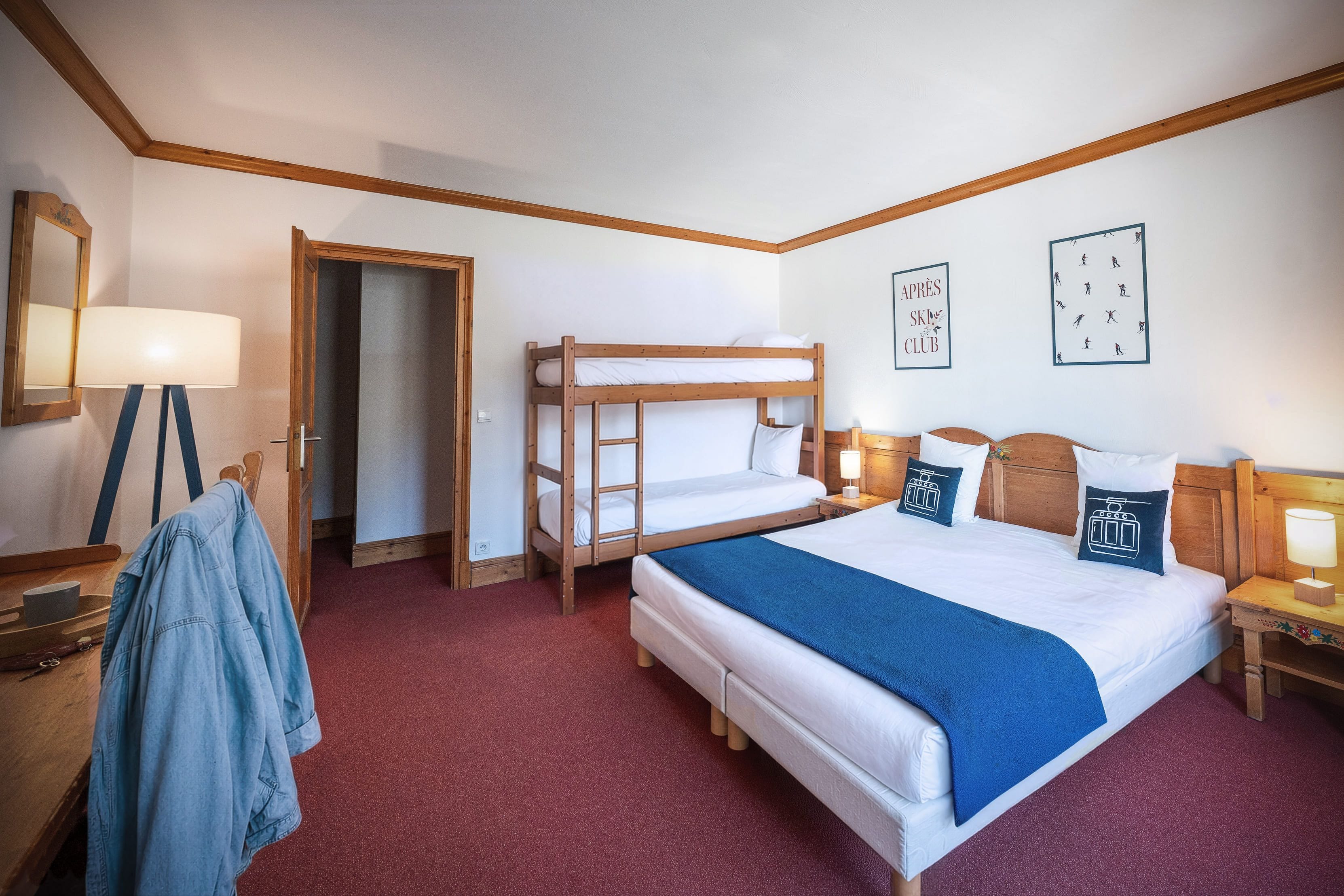 Ein Zimmer mit Etagenbett, Schreibtisch mit Lampe, Stuhl und Kleiderständer.