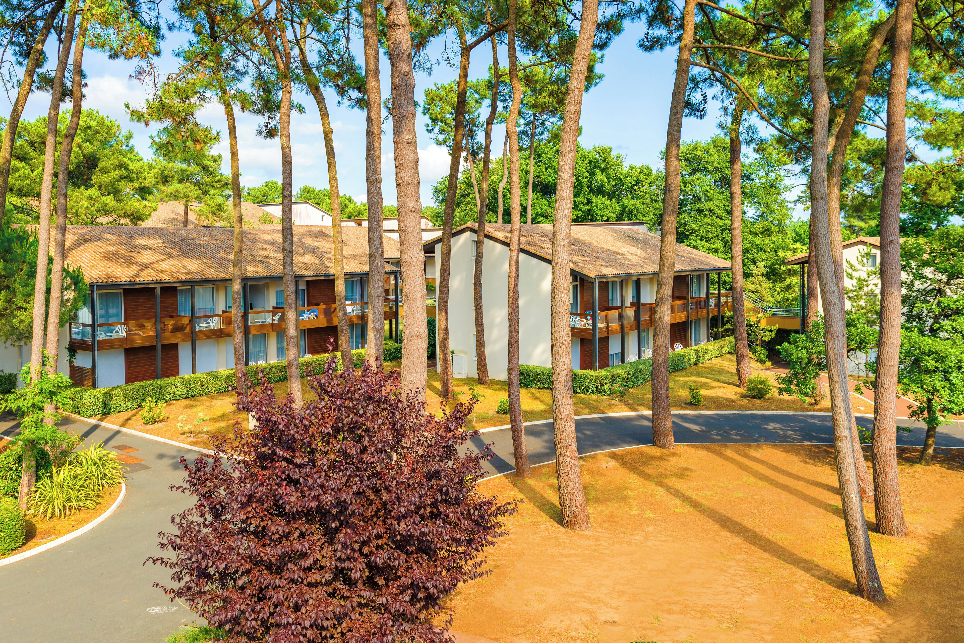 Ein Resort mit mehreren Gebäuden, einer gepflasterten Straße und einer gepflegten Landschaft mit Bäumen und Sträuchern.