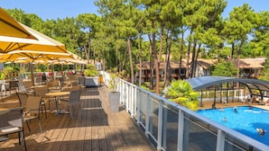 Terraza de madera con mobiliario exterior y zona de piscina.