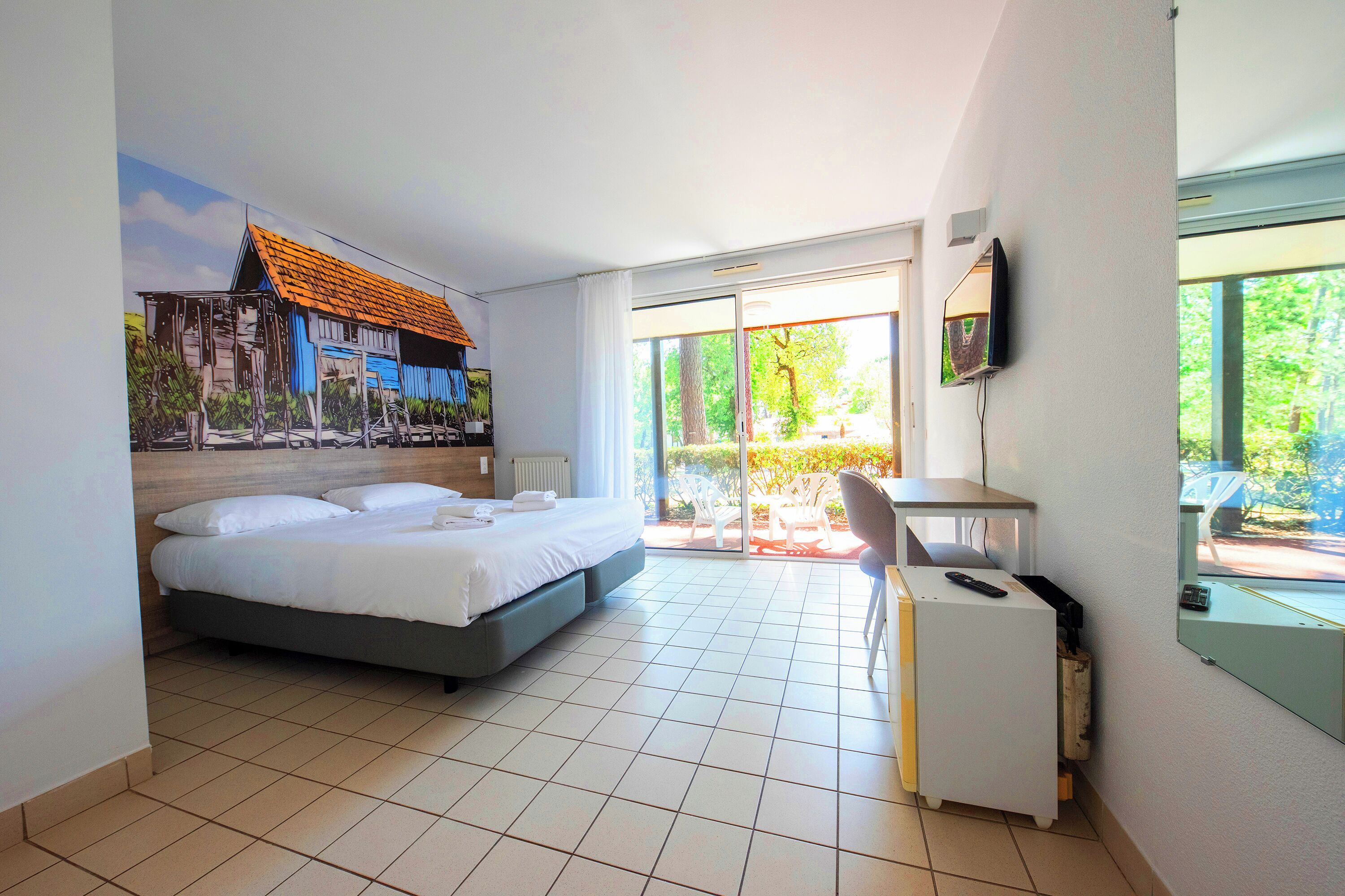 Ein Hotelzimmer mit Bett, Schreibtisch, Stuhl und Fernseher.